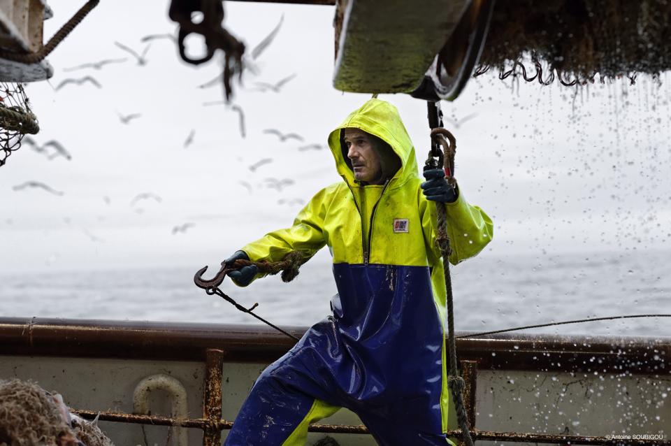 French fisherman on a trawler wearing Stormline fishermans oilskin smock and bib and brace