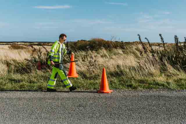 Road worker carrying road cone